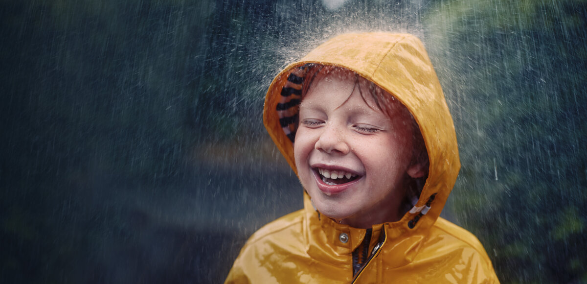Happy smiling little boy out in the rain
